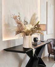 Charger l'image dans la galerie, Composition florale séchée beige et blanche posée sur une console design noire dans un intérieur contemporain.

